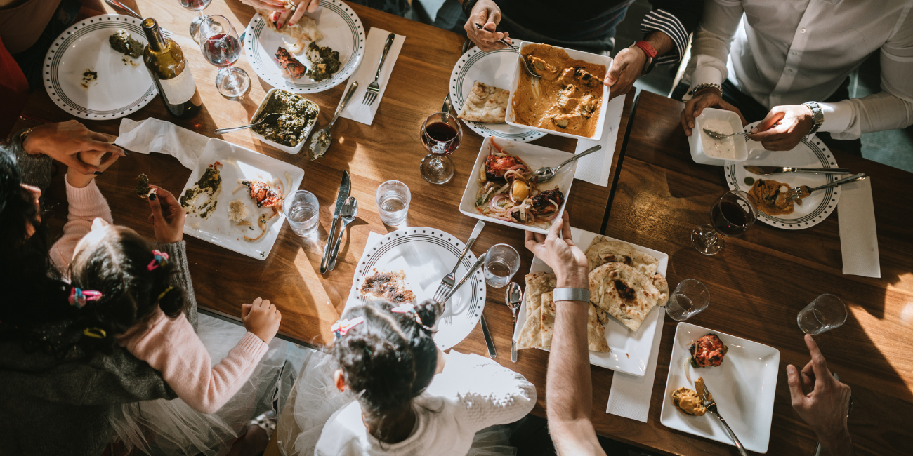 A group of people gathered around a table, enjoying various dishes and drinks at Multi Cuisine Restaurant .