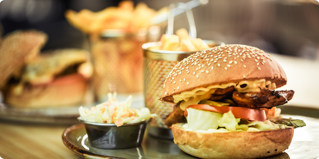 A plate with a juicy hamburger topped with lettuce and tomato, accompanied by a side of golden fries.