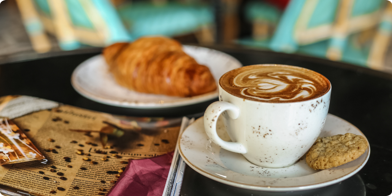 A steaming cup of coffee and a flaky croissant arranged on a rustic table, inviting a delightful morning treat.
