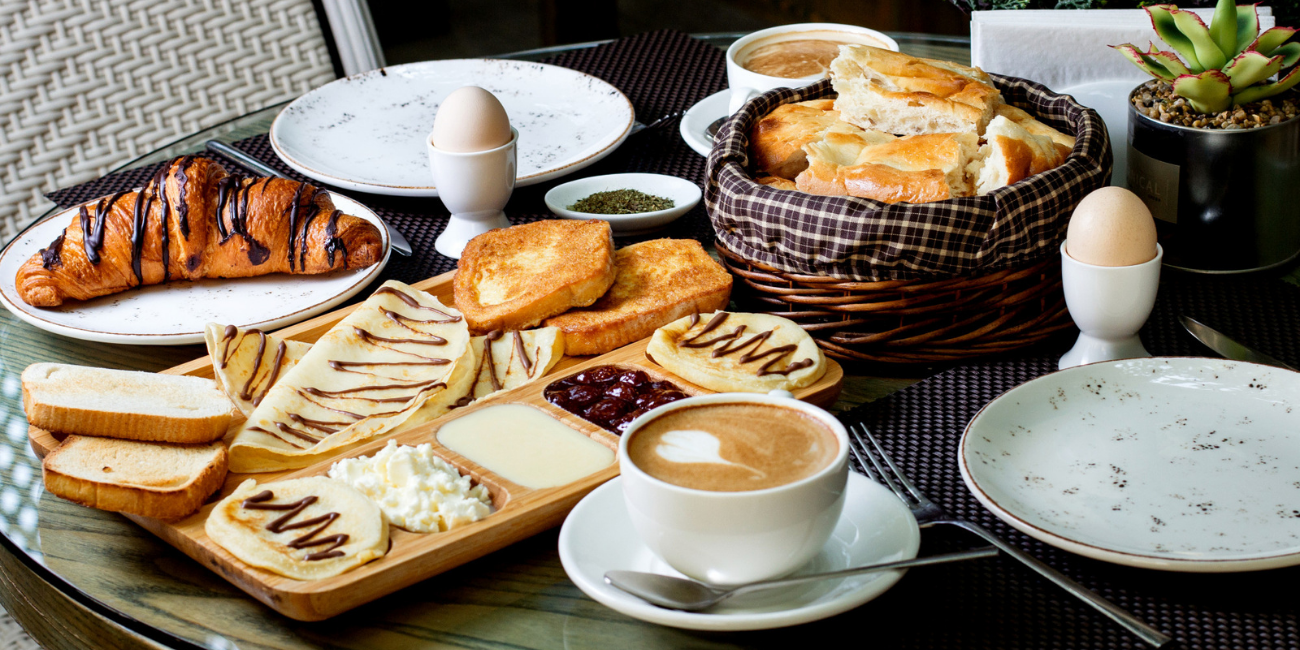 A table set with a basket of bread, a cup of coffee, and various food items arranged neatly.
