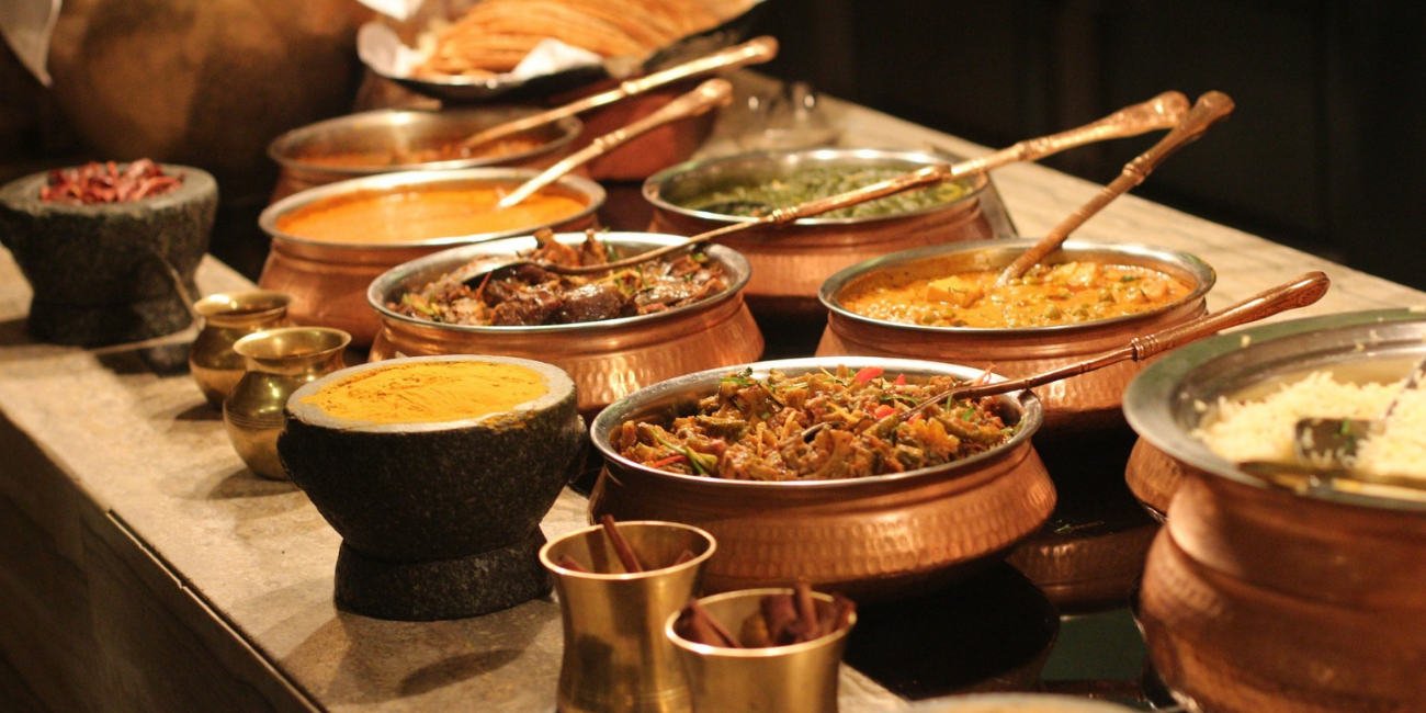 An Indian buffet spread in traditional copper serving bowls and dishes.