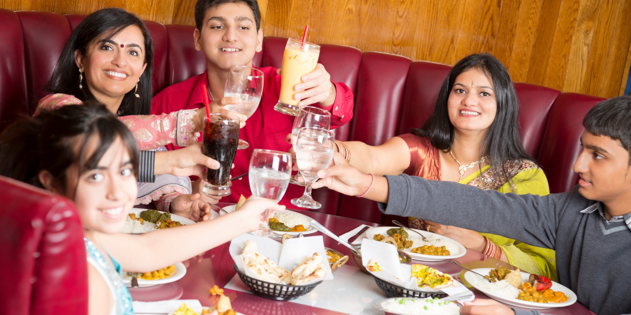Family gathered at a restaurant, joyfully toasting with their drinks in a festive atmosphere.
