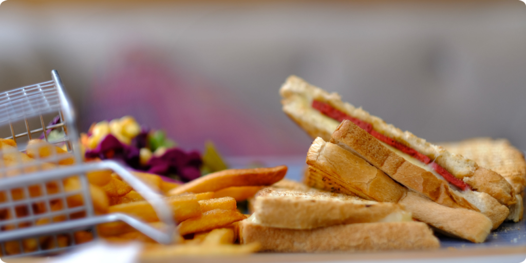 A close-up of a sandwich accompanied by crispy fries on a white plate