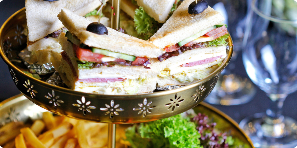 A tray filled with assorted sandwiches and crispy fries placed on a wooden table