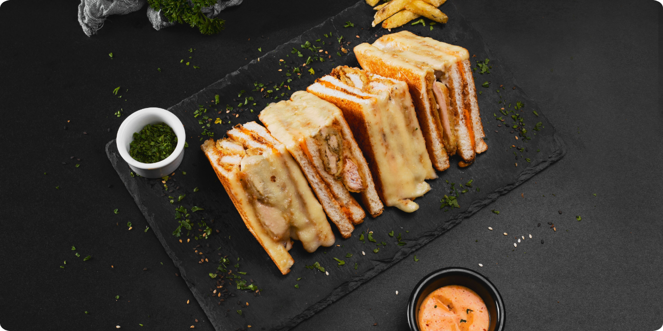 Close-up of a sandwich featuring cheese and sauce, elegantly presented on a black plate