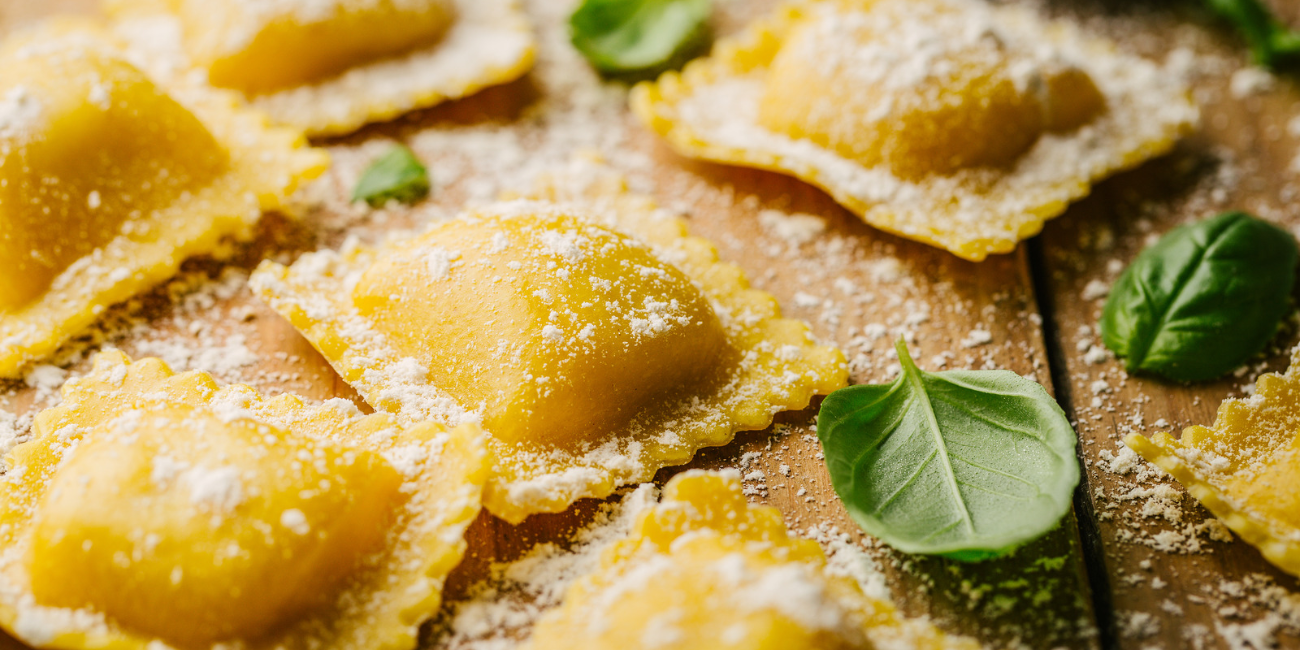 Close-up of uncooked ravioli arranged with fresh basil leaves on a wooden surface